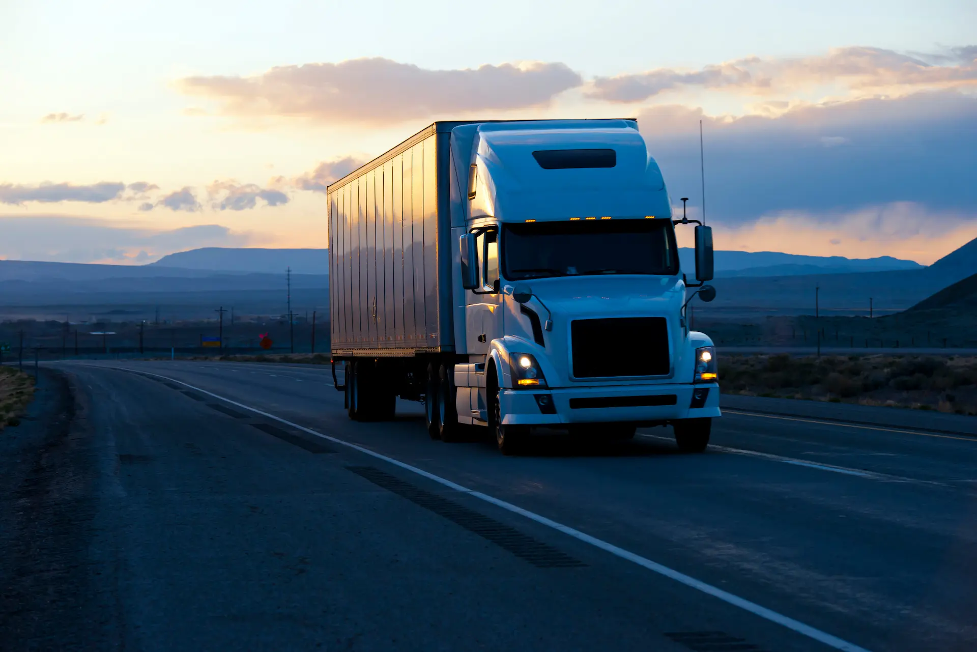 Semi truck traveling on the highway at sunset